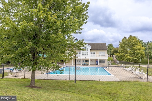 community pool with a patio area, a lawn, and fence