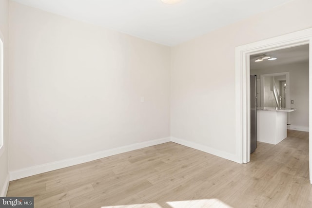 spare room featuring light wood-style floors and baseboards