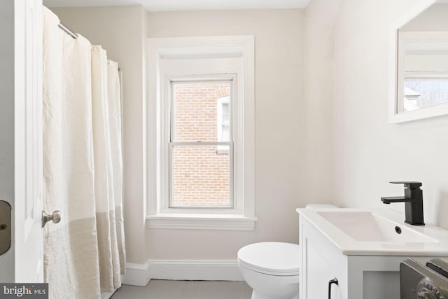 full bath featuring baseboards, vanity, and toilet