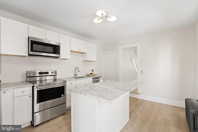 kitchen with appliances with stainless steel finishes, light wood-type flooring, radiator, and white cabinetry