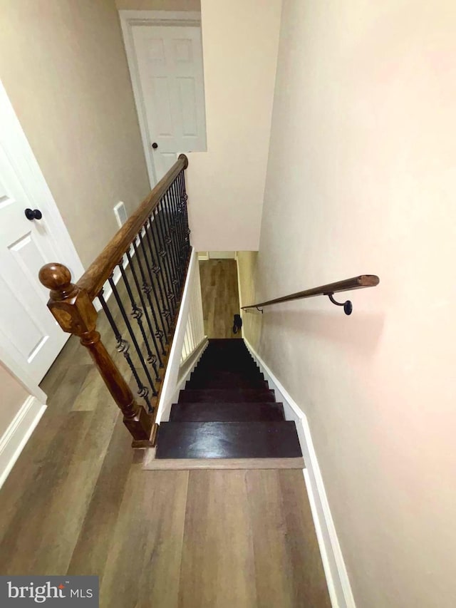 staircase featuring baseboards and wood finished floors