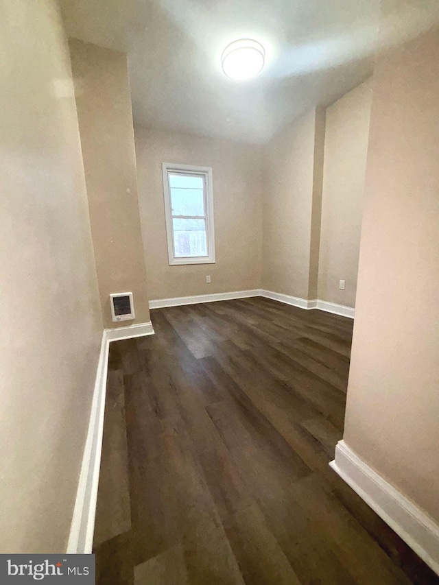 spare room with baseboards, visible vents, and dark wood finished floors