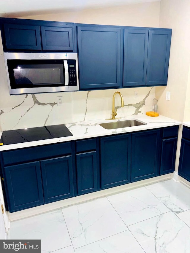 kitchen with stainless steel microwave, a sink, and blue cabinetry