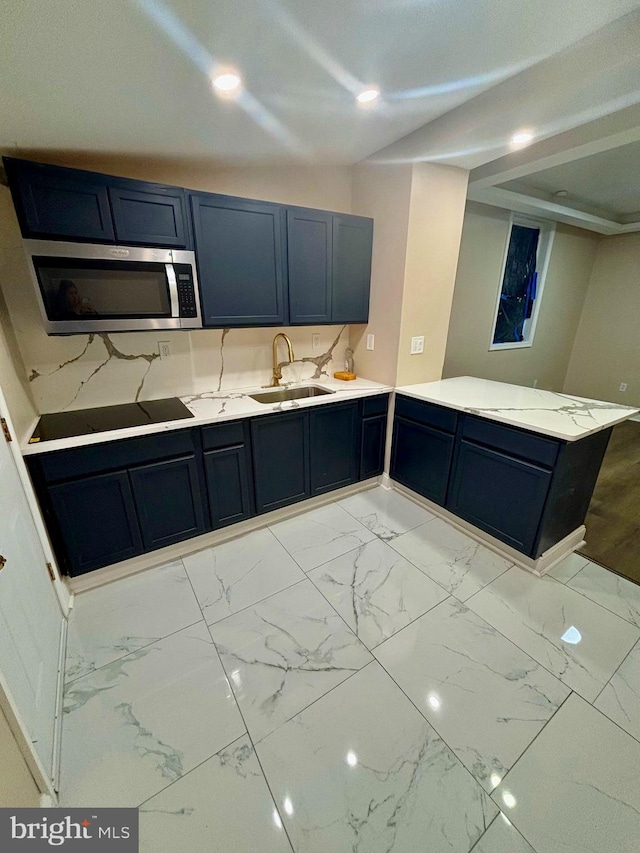 kitchen with stainless steel microwave, a peninsula, marble finish floor, black electric stovetop, and a sink