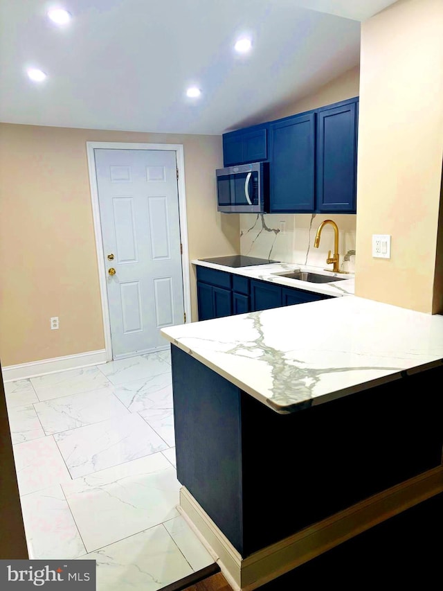 kitchen featuring stainless steel microwave, a peninsula, marble finish floor, blue cabinetry, and a sink