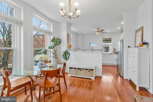 dining area with light wood finished floors, plenty of natural light, visible vents, and ceiling fan with notable chandelier