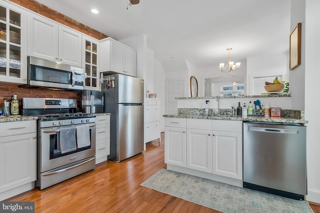 kitchen with stainless steel appliances, light wood-type flooring, and white cabinets