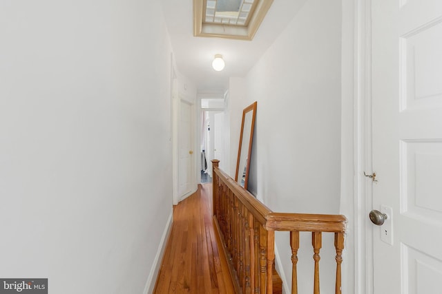 hallway featuring light wood-type flooring, baseboards, and an upstairs landing