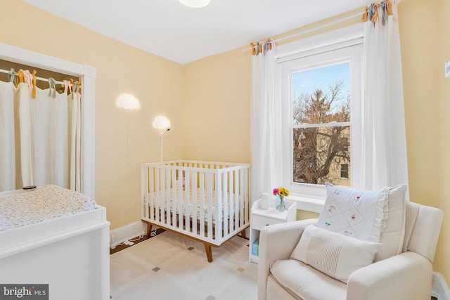 bedroom with a nursery area, multiple windows, and baseboards