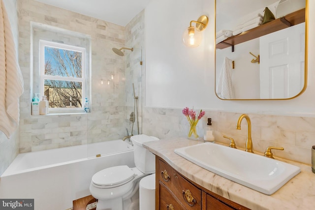 bathroom with toilet, a wainscoted wall, shower / bath combination, vanity, and tile walls