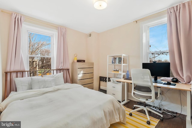 bedroom featuring visible vents, baseboards, and wood finished floors