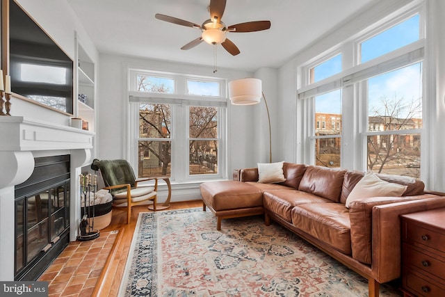 living room with a fireplace with flush hearth, light wood-type flooring, plenty of natural light, and ceiling fan