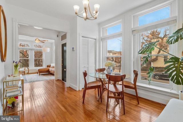 dining space with light wood finished floors, baseboards, arched walkways, and ceiling fan with notable chandelier