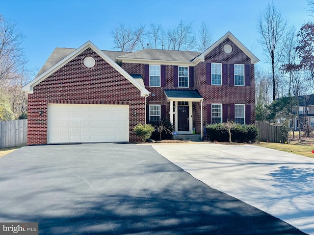 view of front facade with driveway, brick siding, an attached garage, and fence