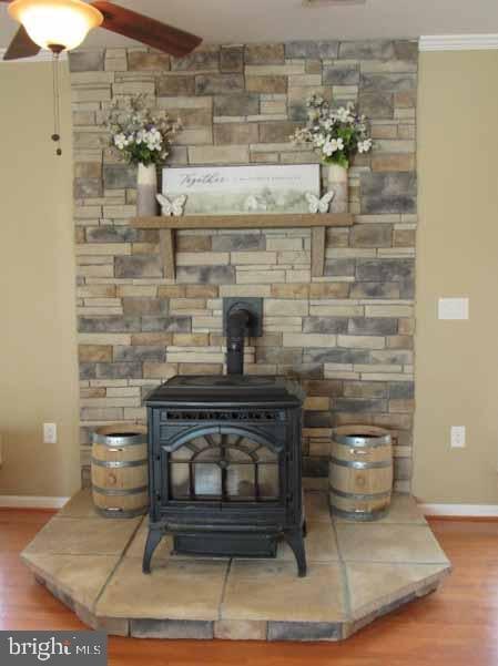 interior details with baseboards, wood finished floors, a wood stove, and ornamental molding