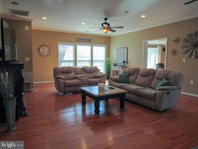 living area with a wealth of natural light, visible vents, baseboards, and wood finished floors