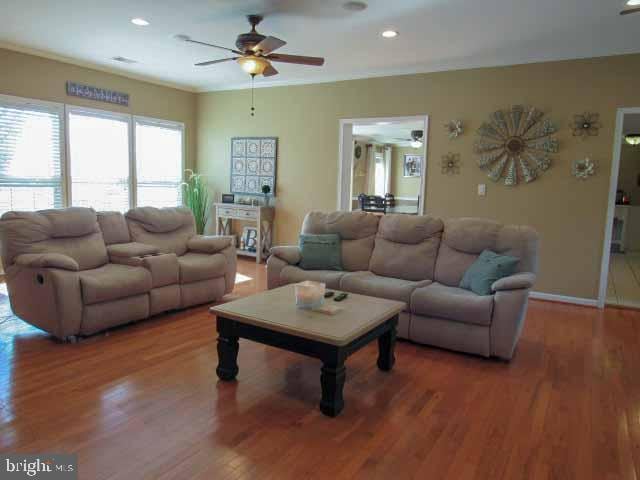 living room featuring wood finished floors, baseboards, recessed lighting, ceiling fan, and crown molding