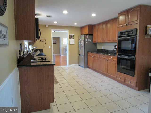 kitchen with visible vents, dobule oven black, dark countertops, freestanding refrigerator, and recessed lighting