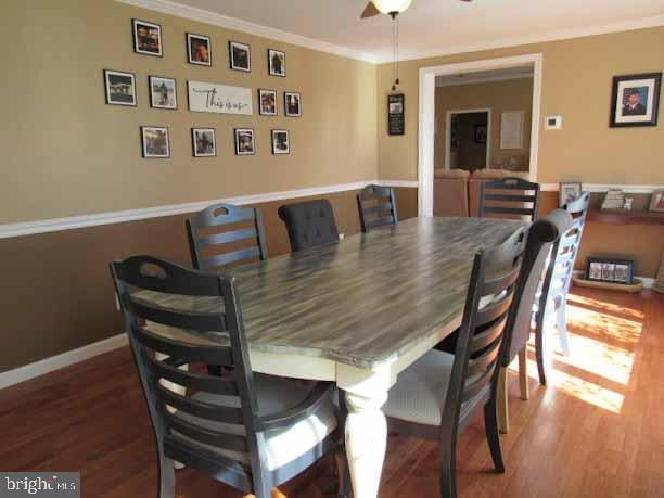 dining area featuring baseboards, a ceiling fan, wood finished floors, and crown molding