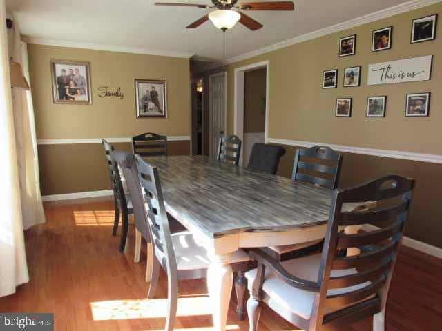 dining room featuring ceiling fan, baseboards, light wood-type flooring, and ornamental molding