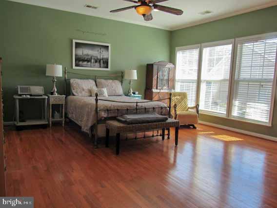 bedroom featuring wood finished floors, visible vents, and baseboards