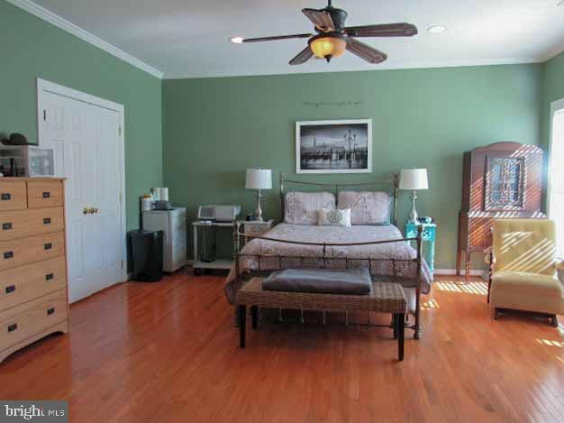 bedroom featuring baseboards, a ceiling fan, wood finished floors, and crown molding