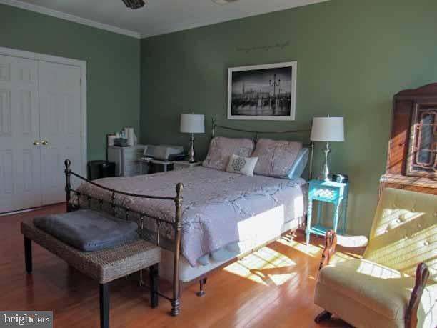 bedroom featuring wood finished floors and crown molding