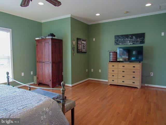 bedroom with crown molding, recessed lighting, wood finished floors, and baseboards