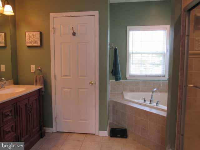 bathroom featuring tile patterned floors, a bath, and vanity