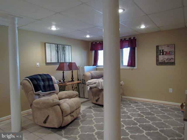 sitting room featuring recessed lighting, a drop ceiling, baseboards, and decorative columns