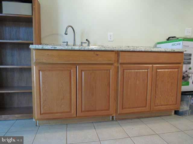 interior space with light stone counters, light tile patterned flooring, brown cabinetry, and a sink