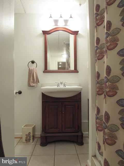 full bath featuring vanity, tile patterned floors, and baseboards