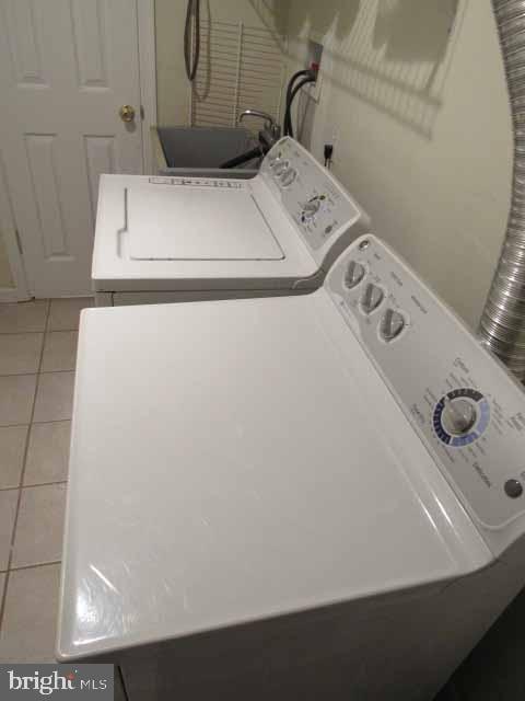 laundry area with laundry area, light tile patterned floors, and washing machine and clothes dryer