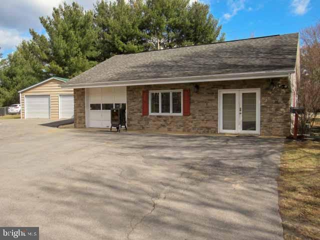 single story home featuring stone siding, french doors, a shingled roof, and a detached garage