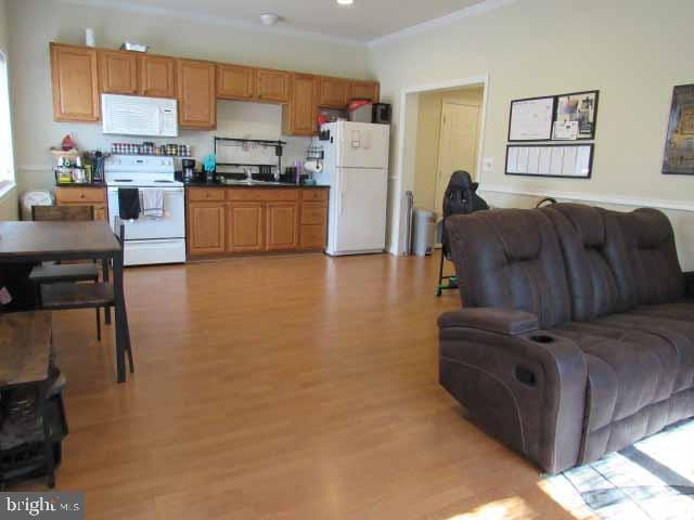 kitchen featuring light wood-type flooring, dark countertops, open floor plan, white appliances, and crown molding