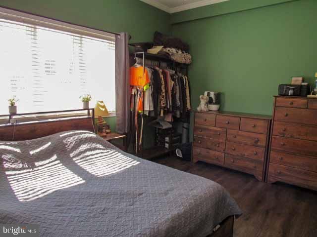 bedroom with crown molding and wood finished floors