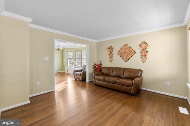 living area with an inviting chandelier, baseboards, wood-type flooring, and ornamental molding