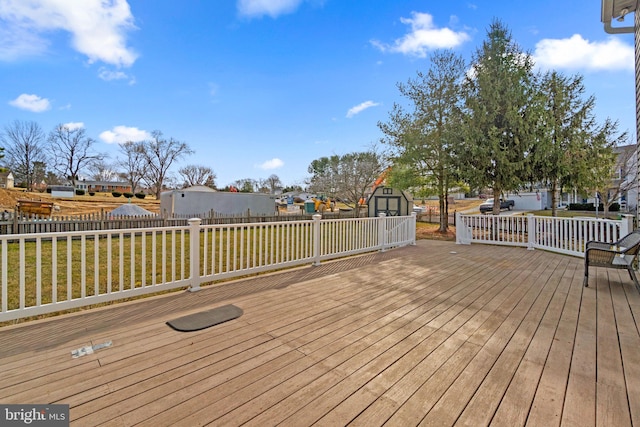 wooden terrace featuring a storage shed, a yard, an outbuilding, and fence