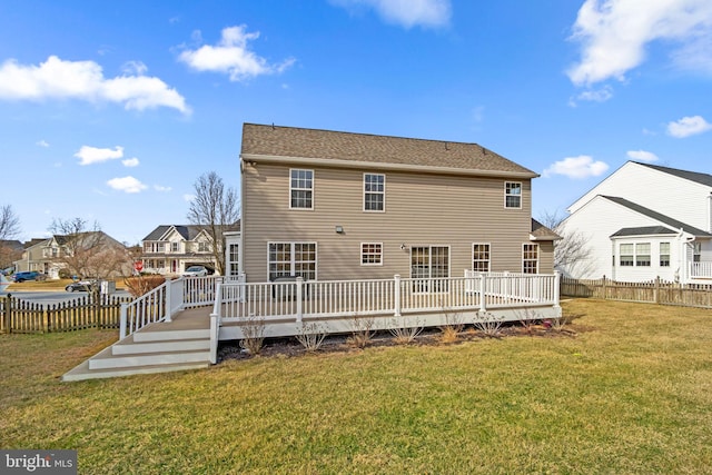 rear view of house with a deck, fence private yard, and a lawn