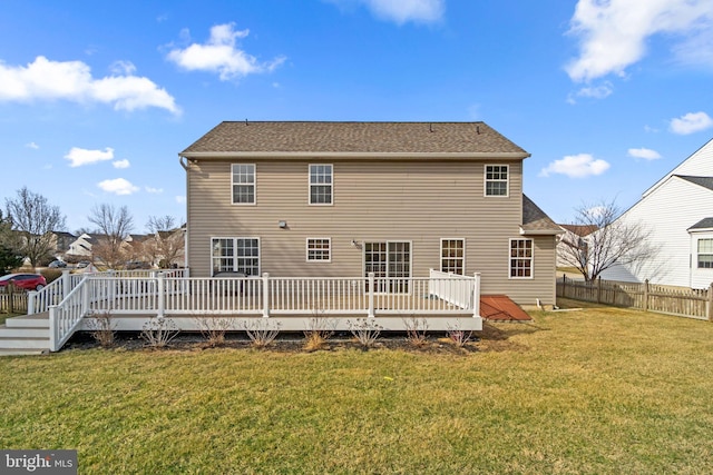 rear view of house featuring a wooden deck, a lawn, and fence