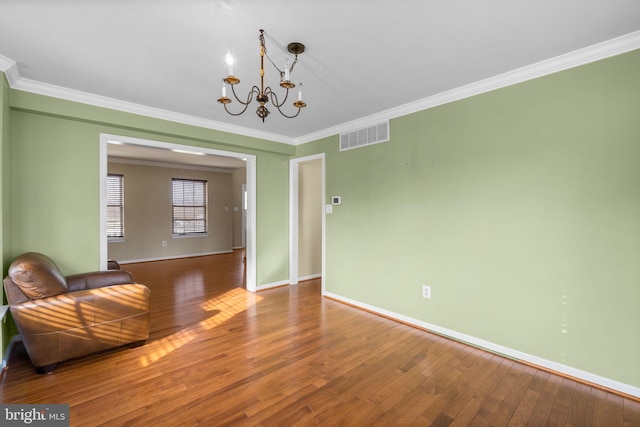 unfurnished dining area with hardwood / wood-style floors, visible vents, baseboards, an inviting chandelier, and crown molding