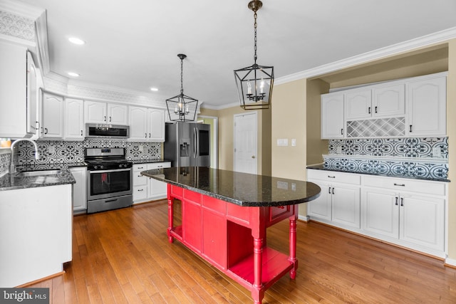 kitchen featuring crown molding, hardwood / wood-style floors, appliances with stainless steel finishes, white cabinetry, and a sink