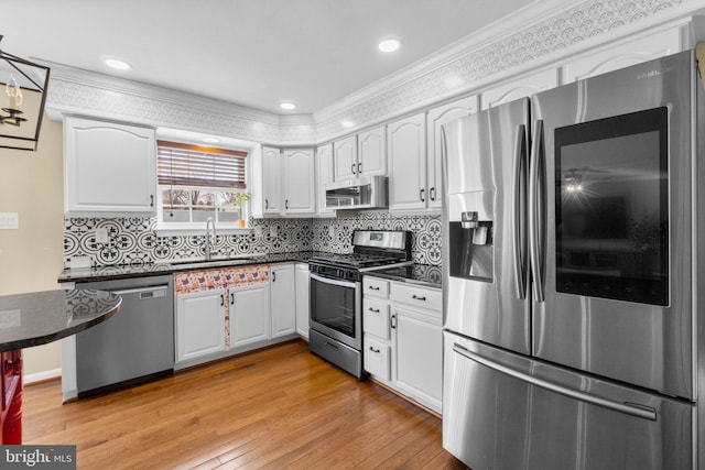 kitchen featuring backsplash, light wood-style flooring, appliances with stainless steel finishes, white cabinetry, and a sink