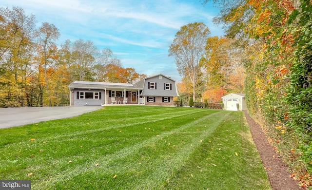 tri-level home featuring a storage shed, covered porch, an outdoor structure, a gambrel roof, and a front lawn