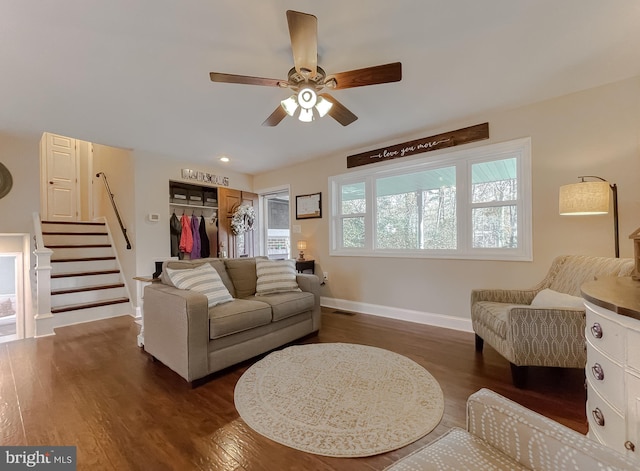 living area with dark wood finished floors, visible vents, stairway, ceiling fan, and baseboards