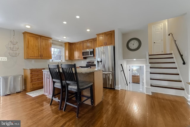 kitchen with appliances with stainless steel finishes, dark wood-style flooring, a kitchen island, and recessed lighting