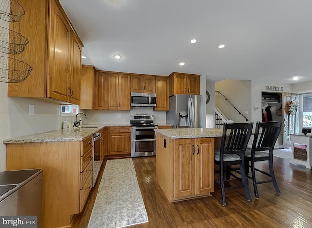 kitchen featuring recessed lighting, a sink, a kitchen island, appliances with stainless steel finishes, and dark wood-style floors