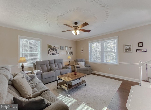 living area featuring a ceiling fan, crown molding, baseboards, and wood finished floors