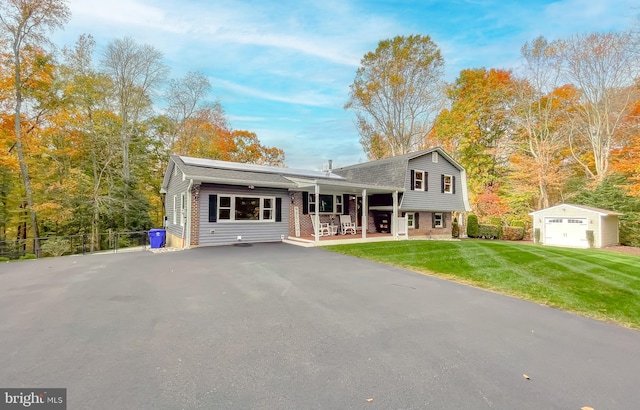 split level home featuring an outbuilding, a gambrel roof, fence, driveway, and a front lawn