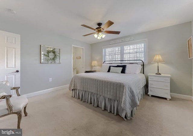 bedroom featuring baseboards, ceiling fan, ensuite bathroom, and light colored carpet